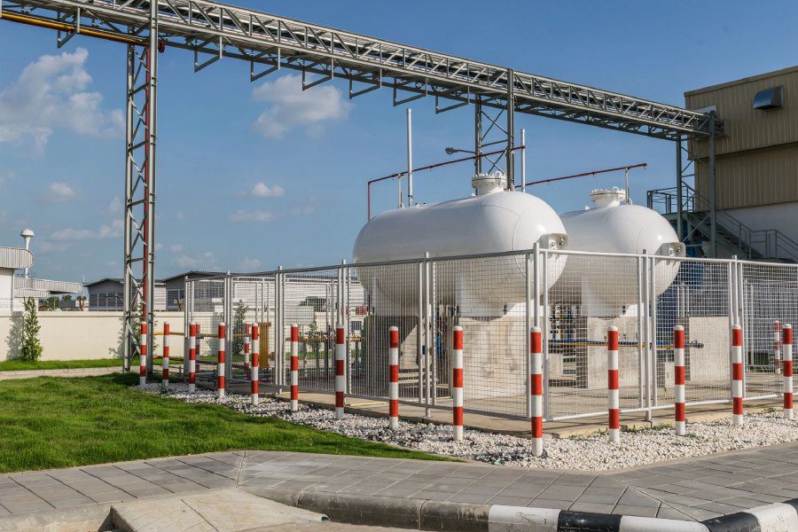 A gas station with two tanks and a fence.