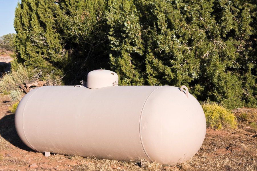 A white tank sitting in the grass near some trees.