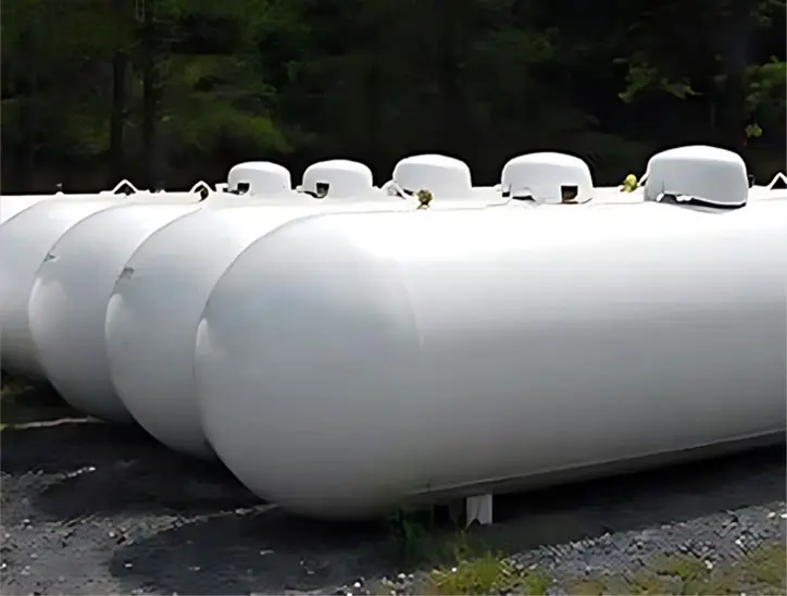 A group of white propane tanks sitting on top of cement.